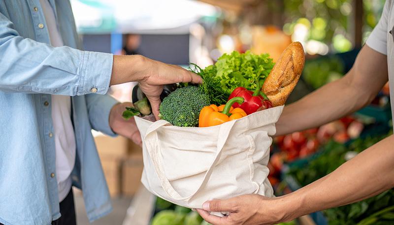 Fresh produce being placed into a shopping bag