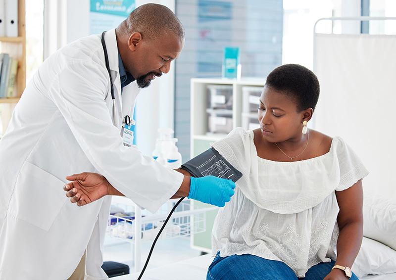 Doctor with patient, placing blood pressure cuff her arm