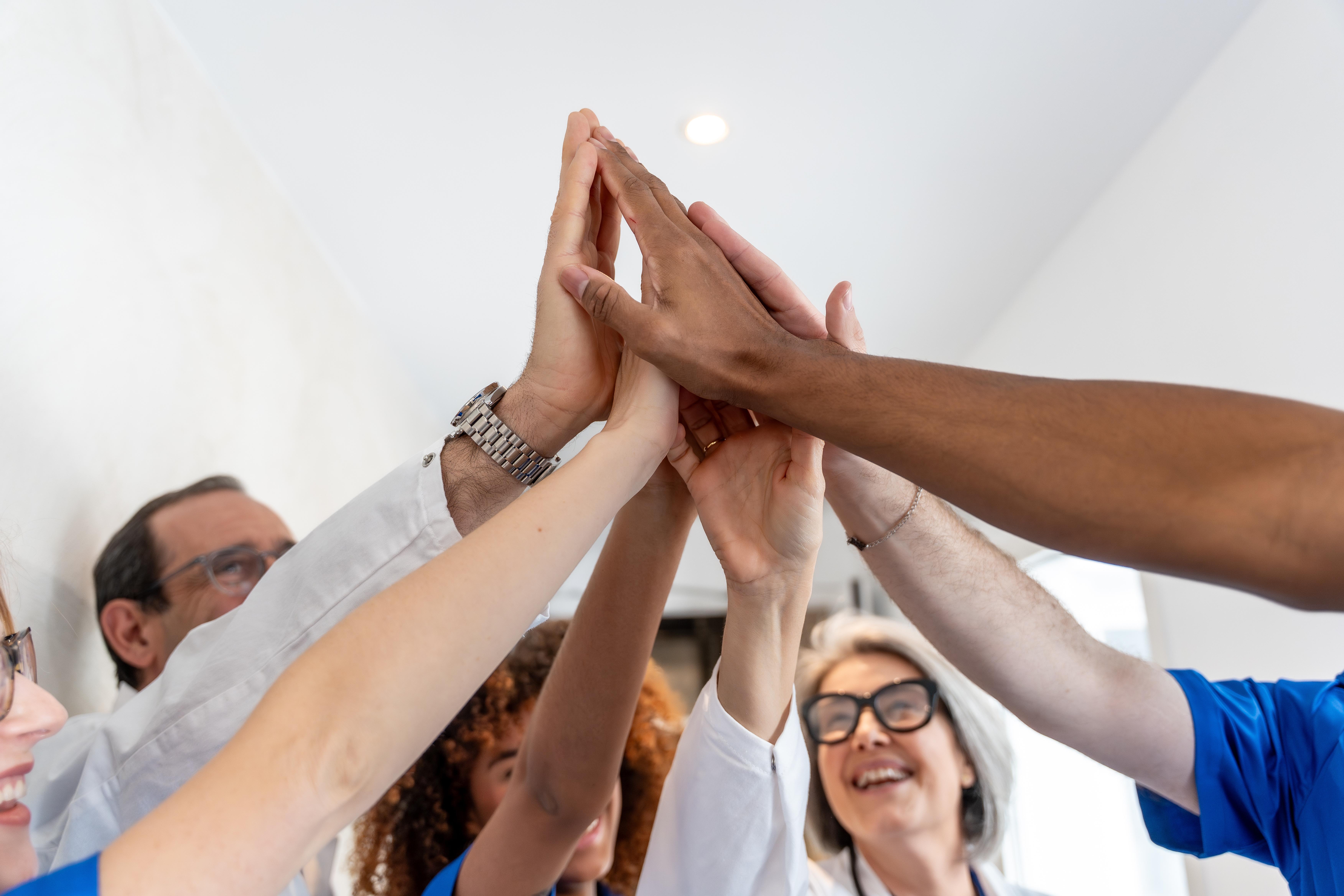 A group of medical professionals do a group high five.