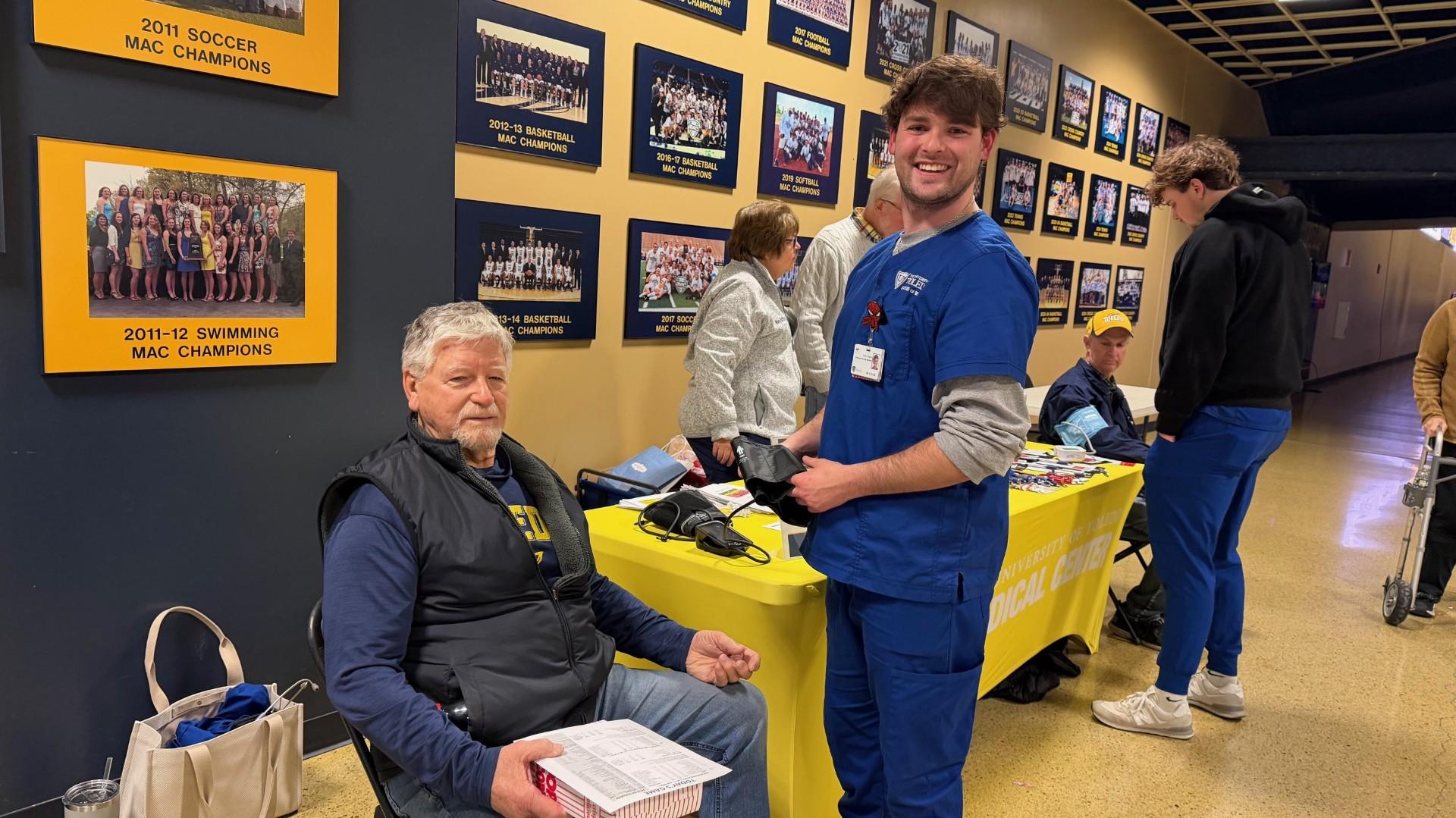 A clinician prepares to check a man’s blood pressure at a UT Health booth