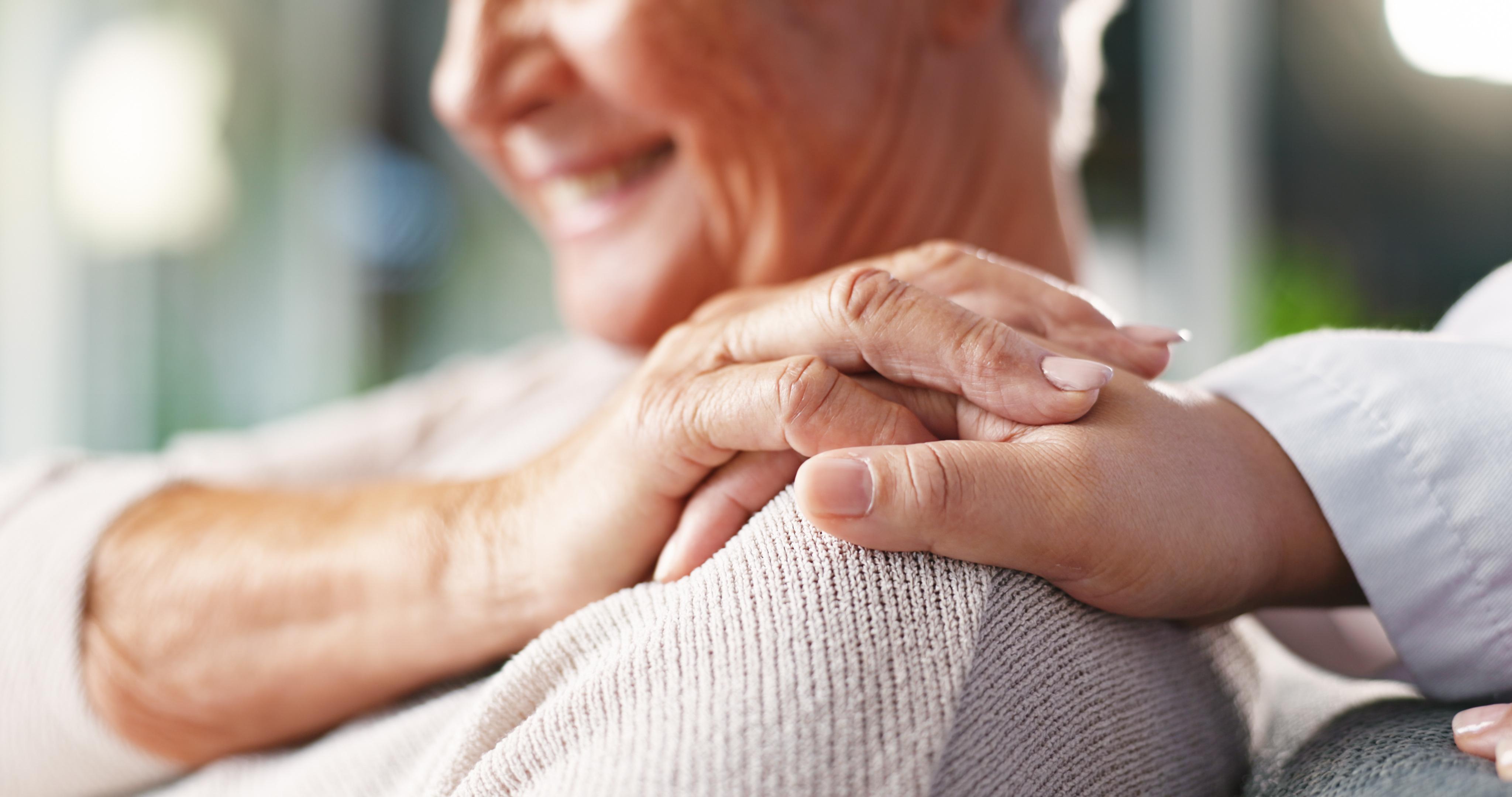 A doctor and smiling senior patient touch hands