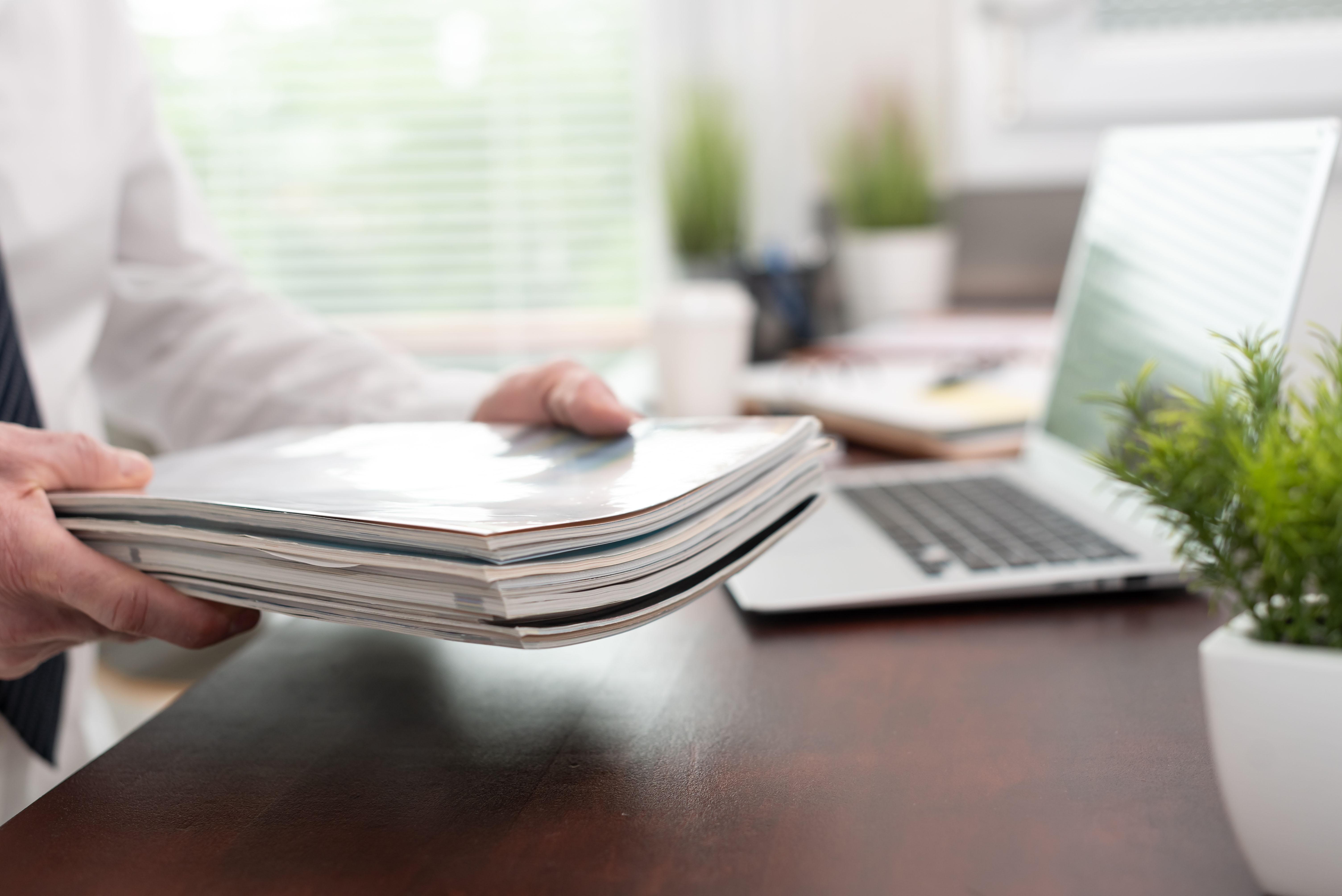 a man holding a stack of publications