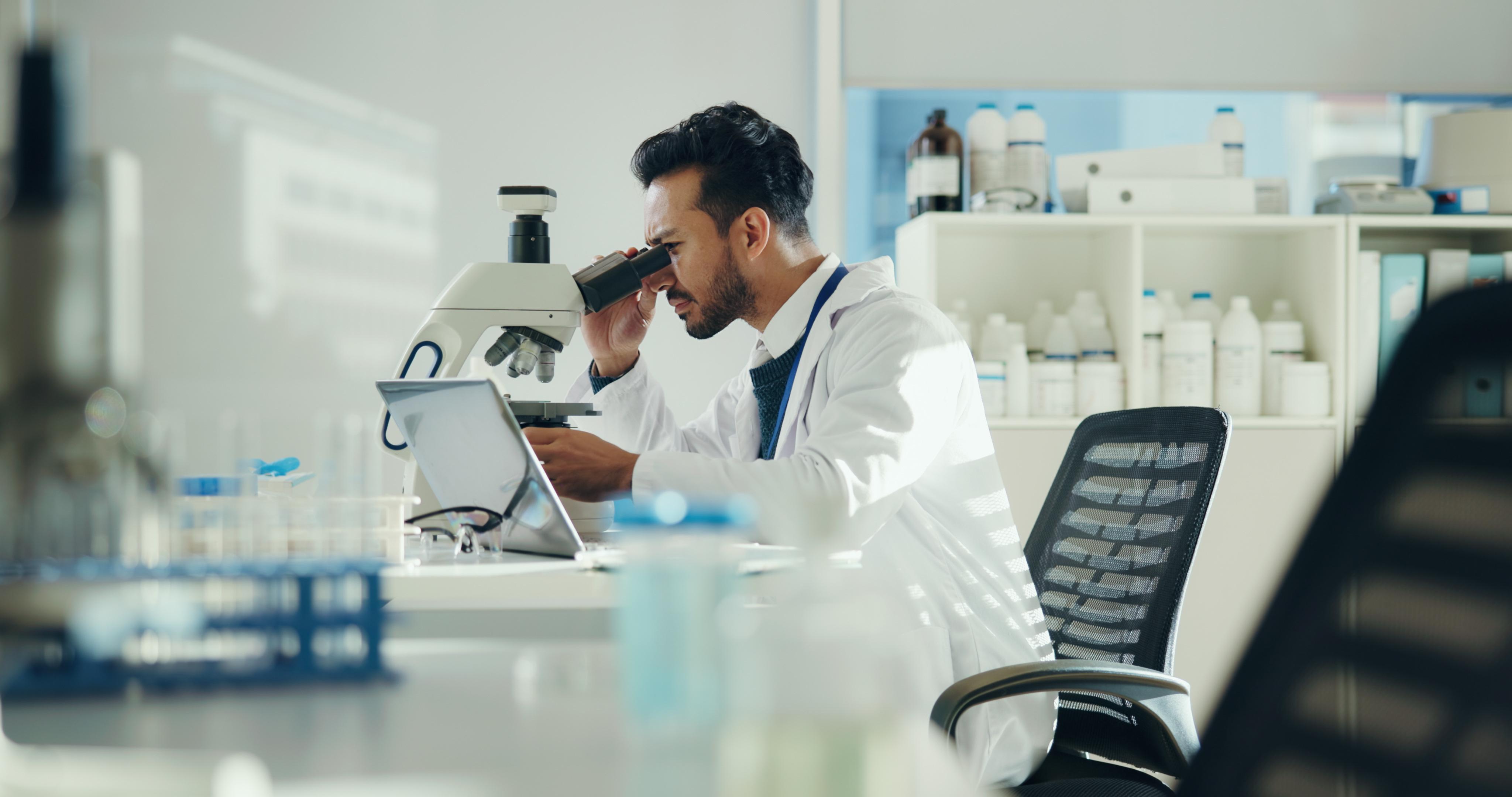 man with microscope in lab for clinical trial